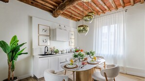 A modern kitchen with white cabinetry, a wooden ceiling, and a dining area with a round table and chairs.
