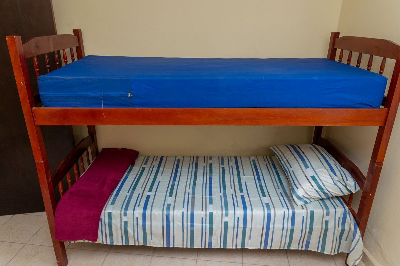 Ein Etagenbett mit einer blauen Matratze oben und einer gestreiften Matratze unten.
