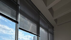Ein Zimmer mit großem Fenster, einer Couch und Blick auf eine Stadtlandschaft.