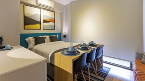 A modern hotel room with a bed, a dining table with chairs, a small kitchen area, and artwork on the wall. - StayHome Frei Caneca Rooftop Gym Jacuzzi (São Paulo)