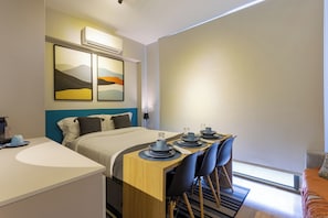 A modern hotel room with a bed, a dining table with chairs, a small kitchen area, and artwork on the wall. - StayHome Frei Caneca Rooftop Gym Jacuzzi (São Paulo)