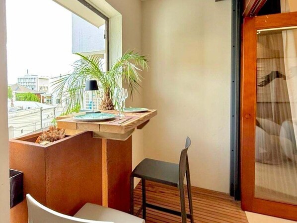 A balcony with a table, chairs, a potted plant, and a view of buildings. - Nice Collection, Elegant One-Bedroom Suite (Saint-Denis)