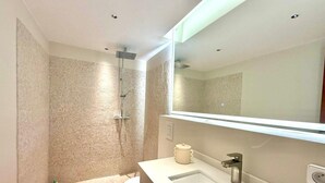 A modern bathroom with a shower, toilet, sink, and a large mirror. - Nice Deluxe, Premium One-Bedroom Apartment (Saint-Denis)