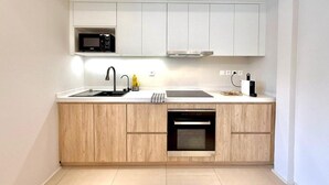 A modern kitchen with white cabinets, a microwave, a sink, a stove, and a dishwasher. - Nice Deluxe, Premium One-Bedroom Apartment (Saint-Denis)