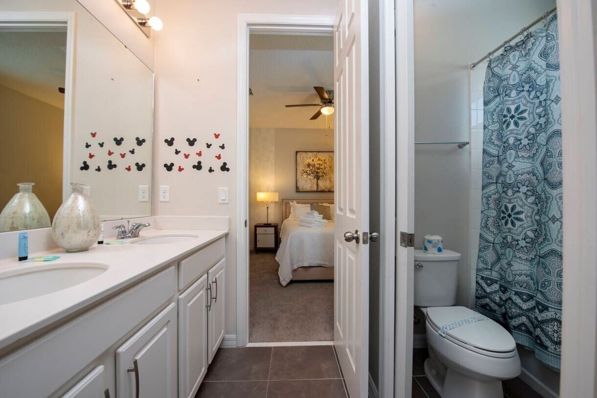 A bathroom with a white sink, a toilet, and a shower curtain with a floral pattern.