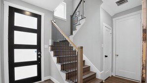 Eine Treppe mit Holzhäusern und schwarzen Geländern, eine schwarze Tür mit Glasfenstern sowie eine weiße Tür.