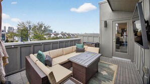 Eine Dachterrasse mit einer Eckcouch, einem Tisch und einem Grill.