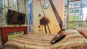 A bedroom with a bed, a television mounted on the wall, and a window with a view of trees. - Number 1 (Blackpool)