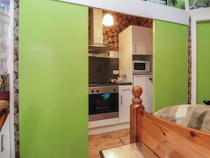 A compact kitchen with a microwave, oven, and a hanging light fixture.