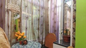 A room with a round table, chairs, a potted plant, and a window with sheer curtains. - Number 1 (Blackpool)