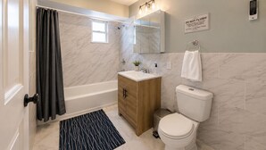 Un baño moderno con bañera, inodoro, tocador y zona de ducha.
