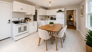 Una cocina moderna con armarios blancos, una mesa de comedor de madera y sillas.