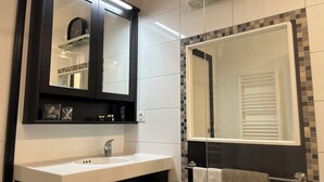 Ein modernes Badezimmer mit einem weißen Waschbecken, einem Spiegel und einem großen Spiegel über dem Waschbecken.