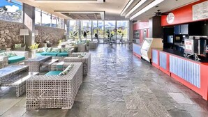 A spacious indoor area with wicker furniture, a stone wall, and a red counter with a menu. - @ Marbella Lane- Trendy Waikiki Oasis Near Beach (Honolulu)