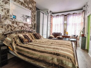 A bedroom with a bed, a chair, a small table, and a window with curtains. - Number 3 (Blackpool)