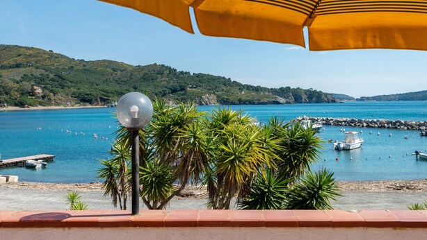 Une vue sur la côte, avec une plage, des bateaux et une côte rocheuse.