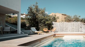 A swimming pool with lounge chairs and a wooden deck. - VILLA CIELO DI TAVOLARA, just a few steps from the sea with breathtaking views. (Porto San Paolo)