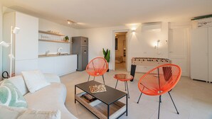 A modern living room with a sofa, a coffee table with a chess set, and two orange chairs. - VILLA CIELO DI TAVOLARA, just a few steps from the sea with breathtaking views. (Porto San Paolo)