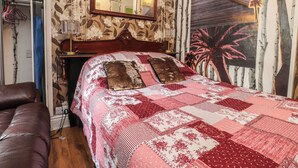 Ein Schlafzimmer mit einem Bett, einer Kommode, einem Spiegel und einer Wand mit einem tropischen Wandgemälde.