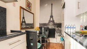 A compact kitchen with a dining area, a large mirror, and a wall-mounted picture of the Eiffel Tower. - Number 6 (Blackpool)