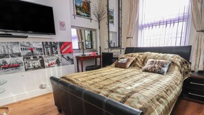 A bedroom with a bed, a television mounted on the wall, a mirror, and a window with curtains. - Number 6 (Blackpool)