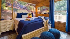 A bedroom with a bed, bedside tables, a nightstand, a window with curtains, and a mural of a bridge. - <10 Min to Lake & DT! Flat Drive! Hot Tub! Games! (Blue Ridge)