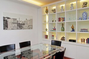 A conference room with a glass table, chairs, and a white shelving unit with decorative items. - BELVEDERE RESIDENCE - BALCONY - JACUZZI - Air Conditioning - Wi-Fi - LUXURY (Roma)