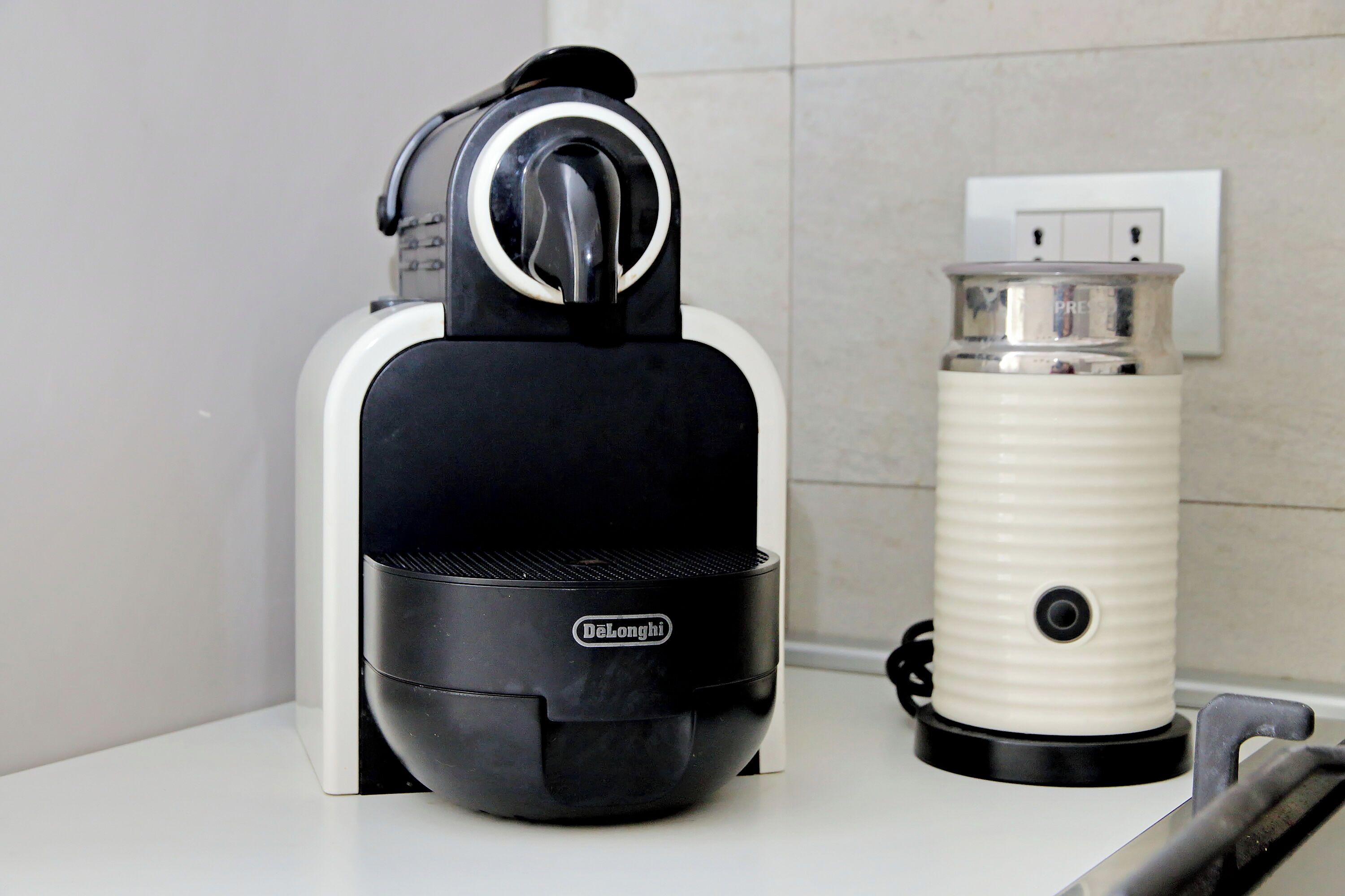 A DeLonghi coffee maker and a white electric kettle on a countertop.