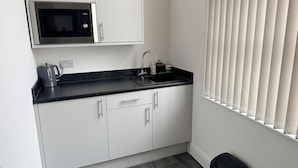 A compact kitchen with a microwave, sink, and cabinets. - Fishergate Residences (Preston)