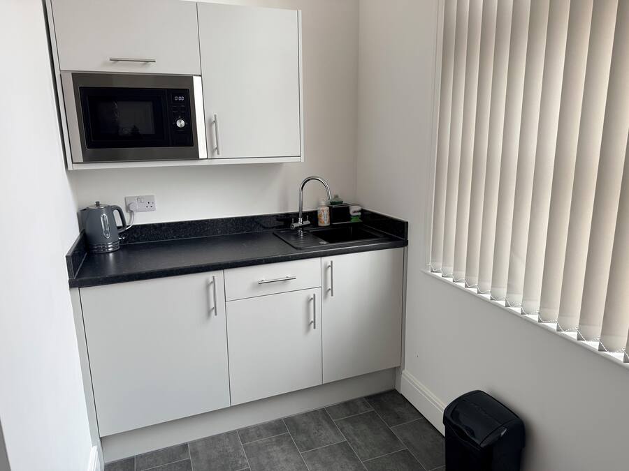 A compact kitchen with a microwave, sink, and cabinets.