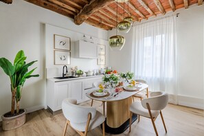 Eine moderne Küche mit weißen Schränken, einem Holztisch mit Stühlen und einem Topfpflanzen.