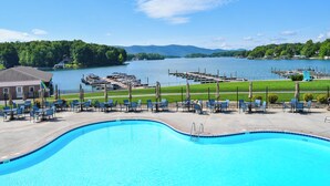 Piscina com espreguiçadeiras, um píer com barcos e vista para o lago.