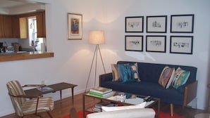 Un soggiorno con divano, poltrone, tavolino e libreria.