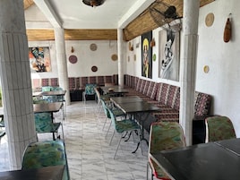 Un comedor con mesas y sillas, un muro con diseño y un ventilador de techo.