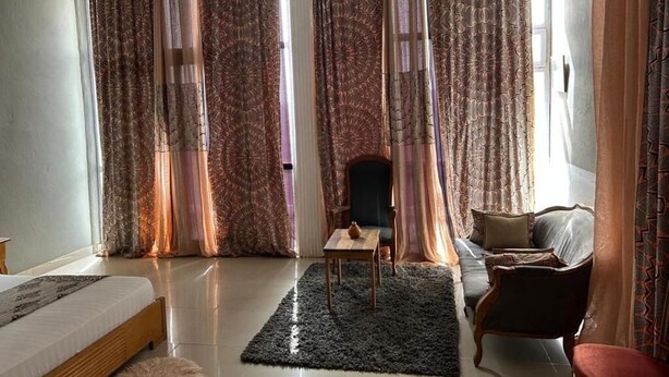 A spacious room with a bed, a chair, a sofa, a small table, and a rug. - Jozene House  (Ngaparou)