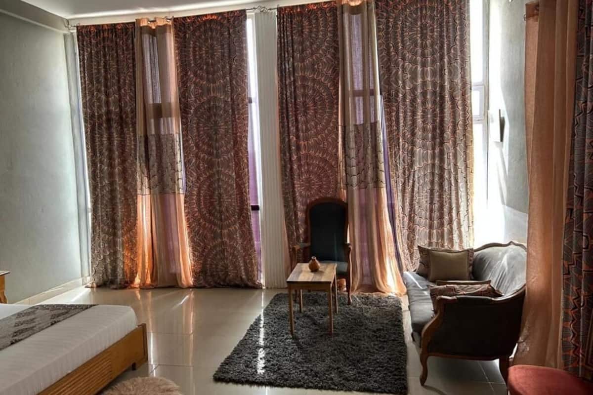 A spacious room with a bed, a chair, a sofa, a small table, and a rug.