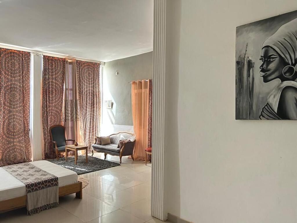Ein Zimmer mit einem Bett, einem Sessel, einer Couch und einem Bild an der Wand.
