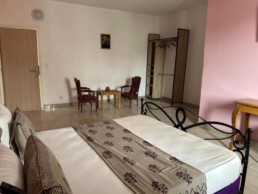Un dormitorio con cama, una silla, una mesa y un espejo.