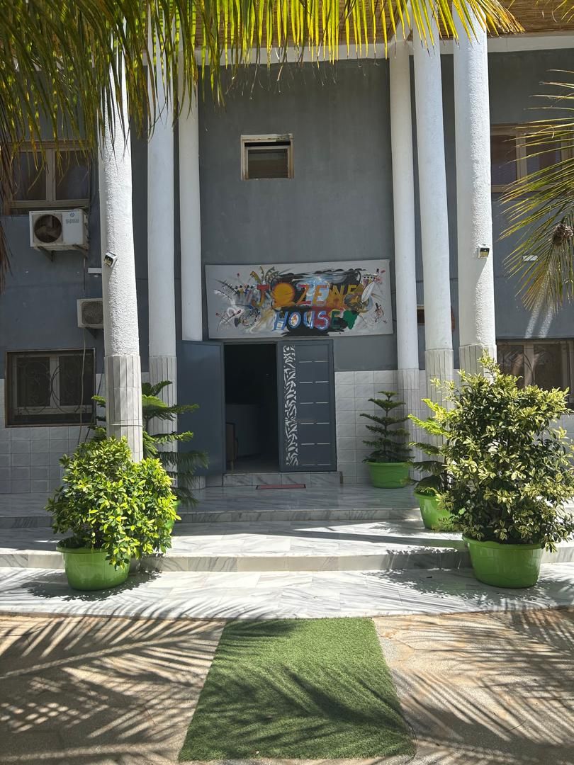A building facade with a central entrance, flanked by two columns, and surrounded by potted plants.