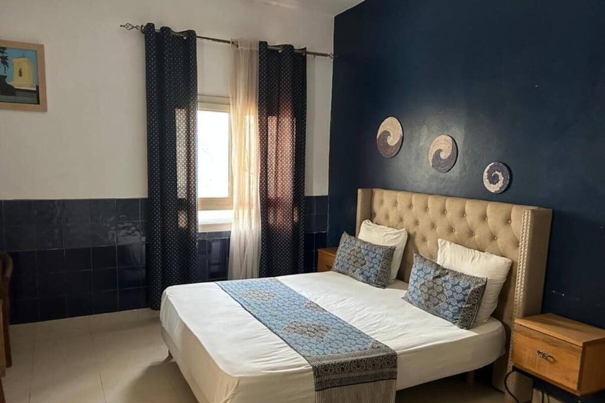 A bedroom with a large bed, a nightstand, a wooden side table, and a wall with decorative circular patterns.