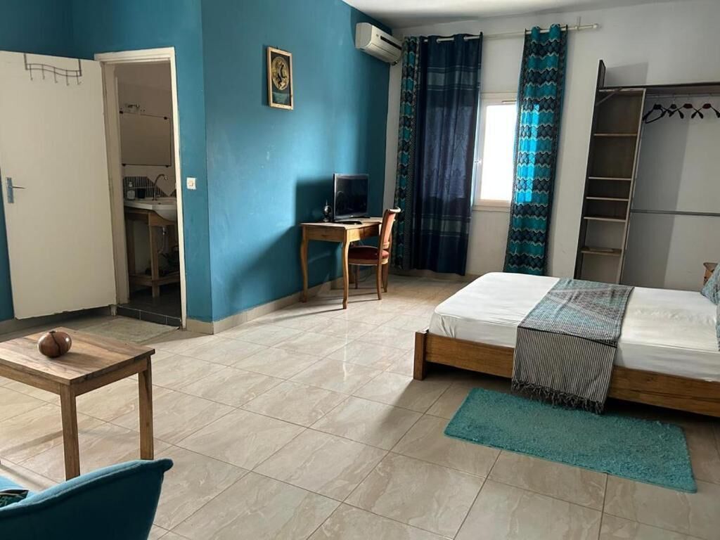 Un dormitorio con cama, escritorio con computadora, silla y armario.