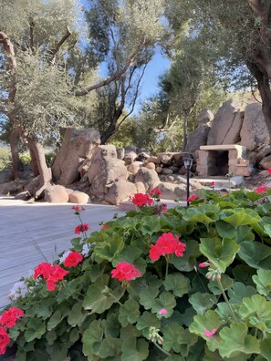A stone bench, large rocks, and flowering plants in a park setting. - Gîte Appicciu – 900m from the Beach (Coti-Chiavari)
