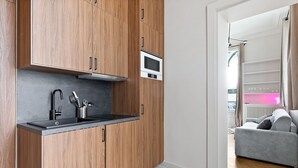 Eine moderne Küche mit Holzausstattung, einer schwarzen Arbeitsplatte, einer eingebauten Mikrowelle und einem Spülbecken mit modernem Wasserhahn und Besteck.