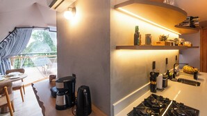 Een moderne keuken met een gasfornuis, koffiezetapparaat en een eethoek met een tafel en stoelen.