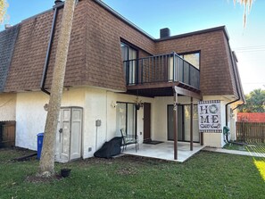 Una casa de dos pisos con un porche cubierto, un garaje y un patio cercado.