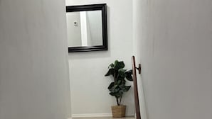 Un escalier avec une rampe, une plante en pot et un miroir accroché au mur.
