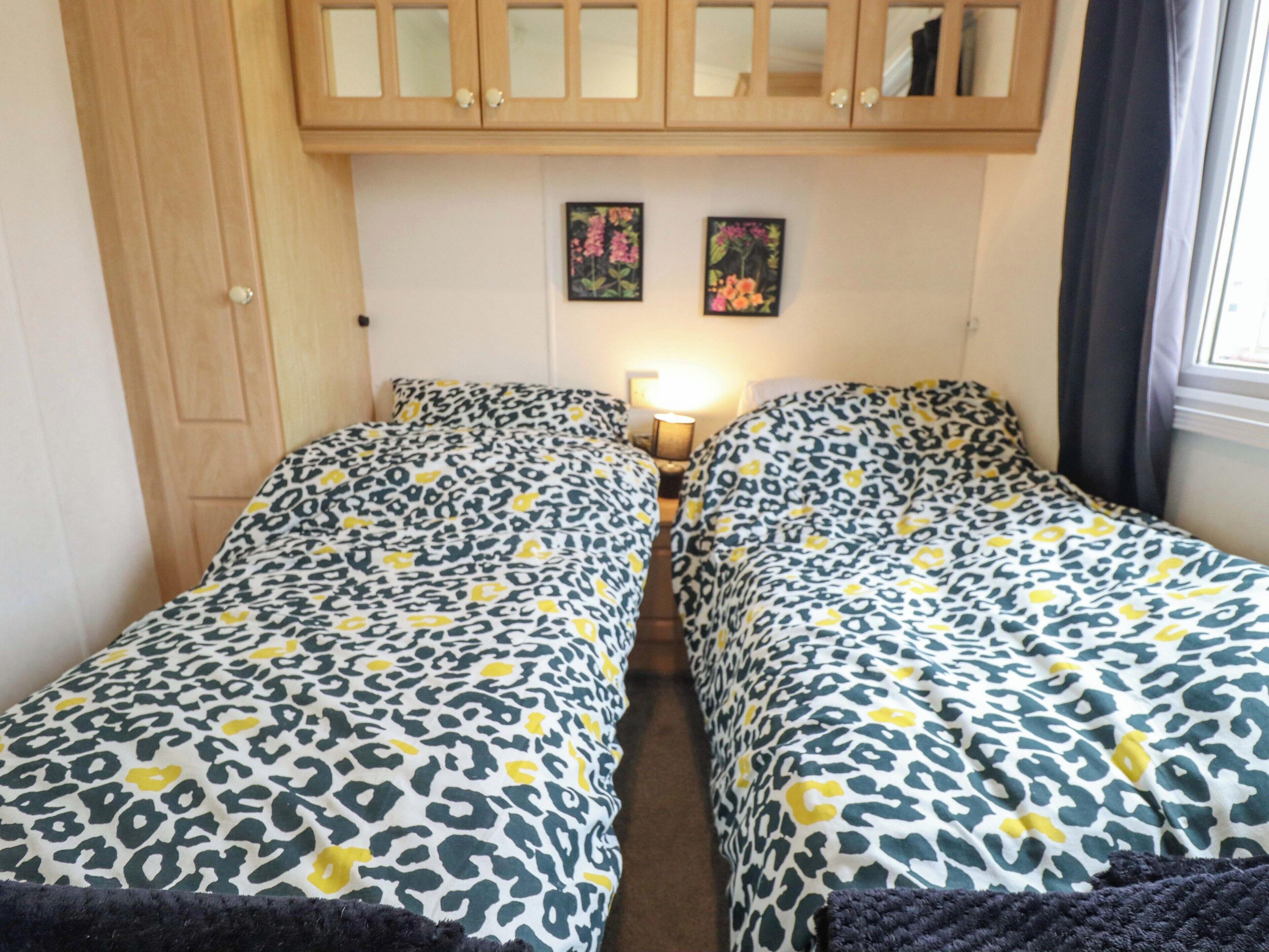 Une chambre avec deux lits, des armoires en bois et deux lampes fixées au mur.