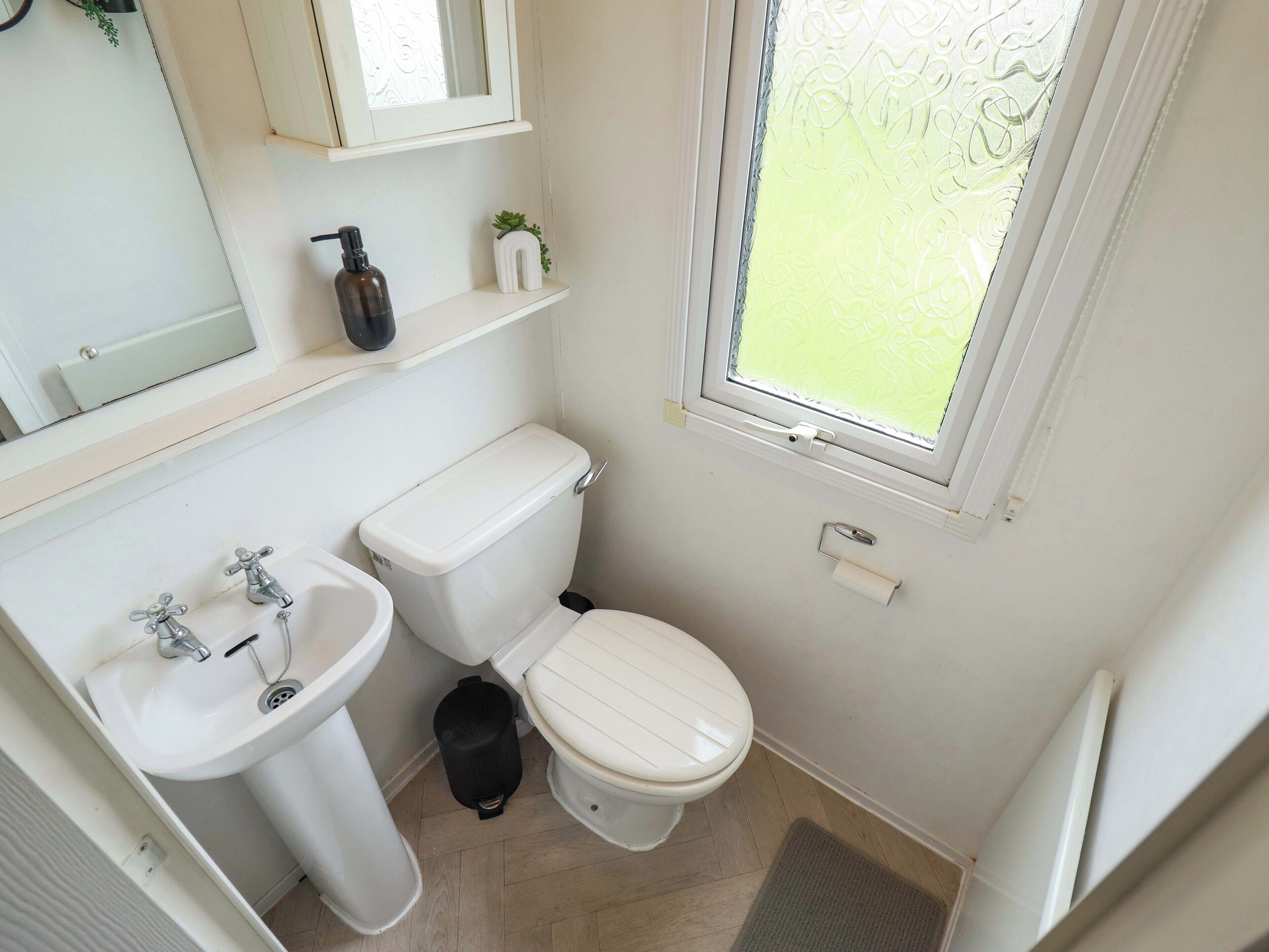 A small, clean bathroom with a toilet, sink, and window.
