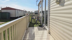 A covered outdoor deck with a railing, a table, and chairs. - Towervans Z11 (Mablethorpe)