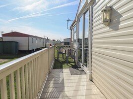Una terraza al aire libre techada con barandilla, una mesa y sillas.